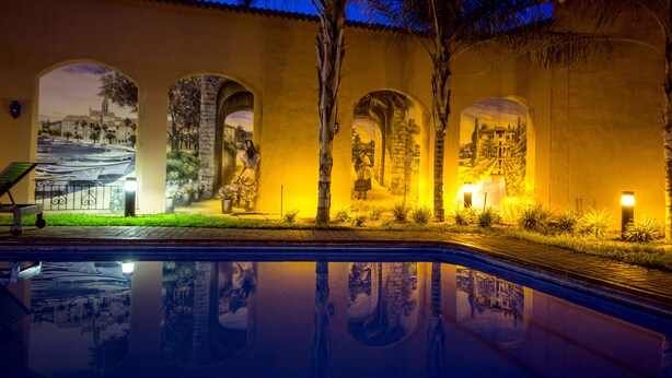 A pool area with a reflection of palm trees and a building facade.