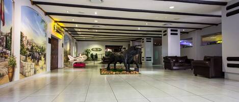 Un hall d’entrée spacieux, orné d’une grande fresque murale, d’une statue de taureau et de sièges en cuir.