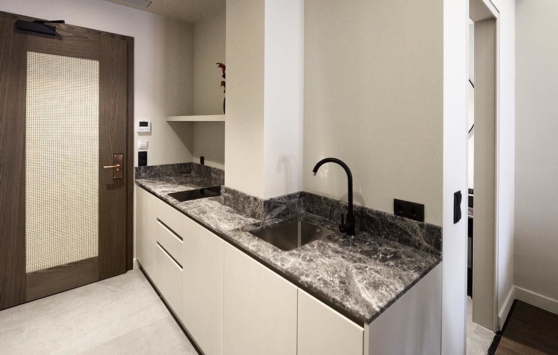 A compact kitchen with a granite countertop, a black faucet, and a small sink.