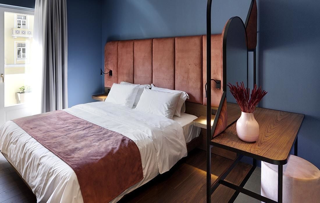 A bedroom with a bed, bedside table, and a window with curtains.
