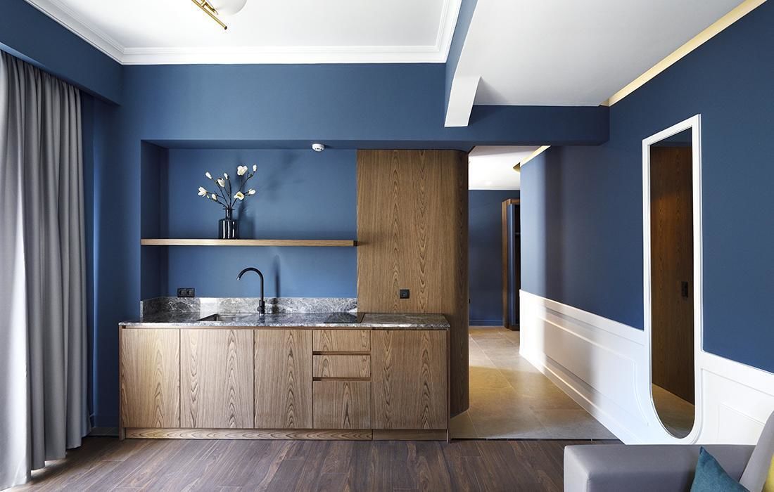 A modern kitchen with a wooden island, built-in shelves, and a marble countertop.