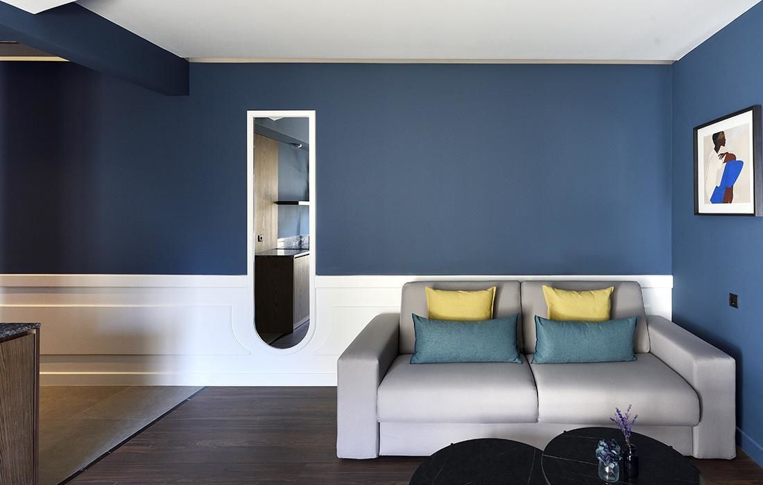 Un salon moderne avec un canapé gris, une table basse noire et un mur d’accent bleu.