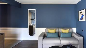 Un salon moderne avec un canapé gris, une table basse noire et un mur d’accent bleu.