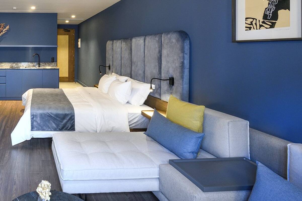 Une chambre d’hôtel moderne équipée d’un lit, d’un canapé, d’un bureau et d’une petite kitchenette.