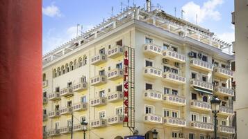 A multi-story hotel with balconies, a prominent red sign, and a clear sky.