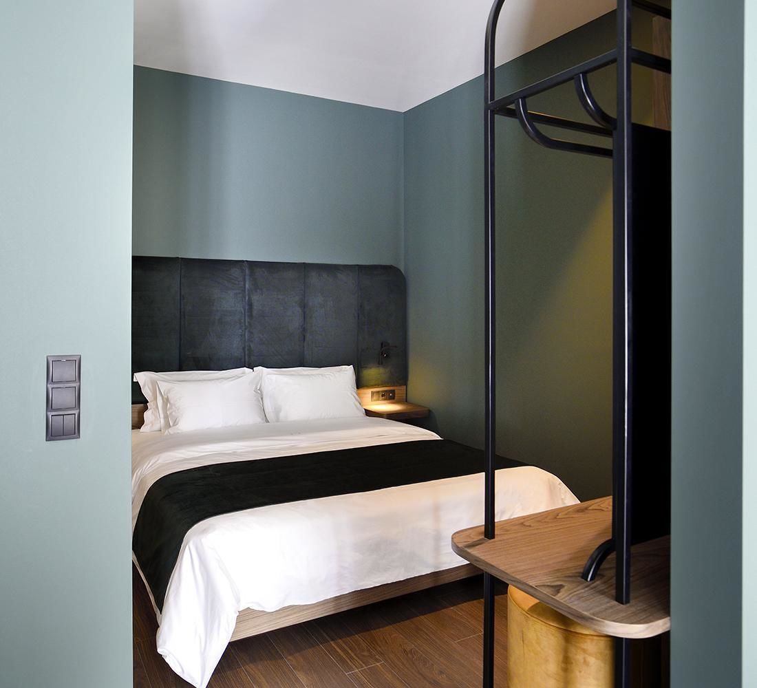 A bedroom with a bed, bedside table, and a wall-mounted shelf.