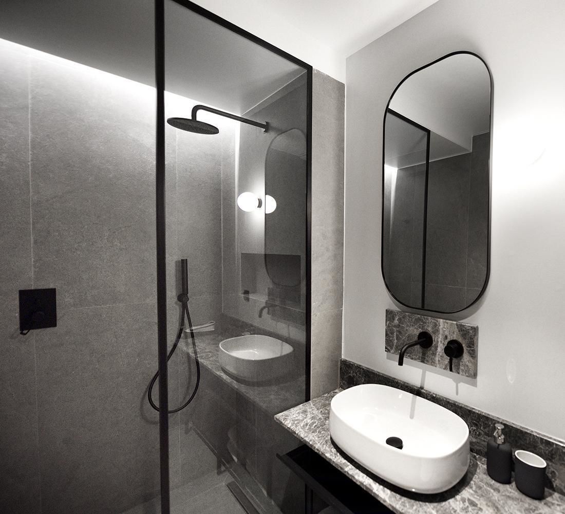 A modern bathroom with a glass-enclosed shower, a sink, and a large mirror.
