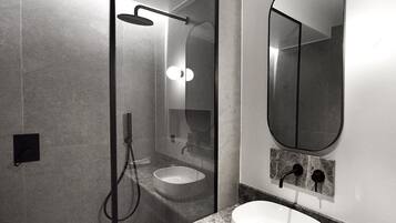 A modern bathroom with a glass-enclosed shower, a sink, and a large mirror.