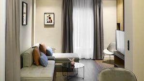 A modern living room with a sofa, a coffee table, and a TV. - Roomore Apartments (Thessaloniki)