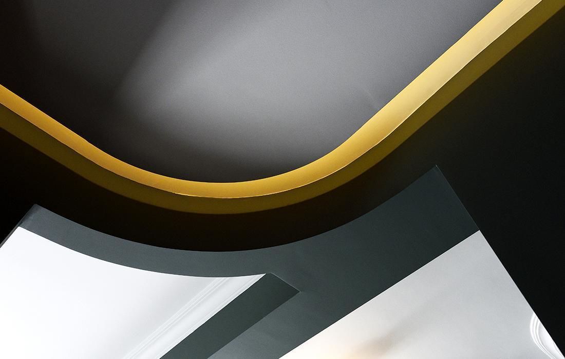 A modern ceiling with a curved design and a gold trim.