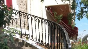 Una escalera curva con barandilla metálica, rodeada de vegetación.