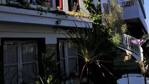 Un edificio de varios pisos con balcones, ventanas amplias y algo de vegetación.