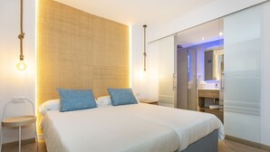 Un dormitorio moderno con una cama grande, mesitas de noche y un vestidor.