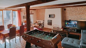 A cozy living room with a foosball table, a television, and a brick wall. - Les Petites Forges Centre Historique Auxonne 120 m2 (5' from A39 freeway) (Auxonne)