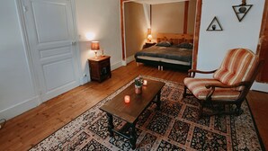 A cozy room with a bed, a chair, a table, and a lamp. - Les Petites Forges Centre Historique Auxonne 120 m2 (5' from A39 freeway) (Auxonne)