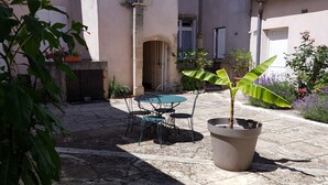 A courtyard with a table and chairs, potted plants, and a building with a door and windows. - Les Petites Forges Centre Historique Auxonne 120 m2 (5' from A39 freeway) (Auxonne)
