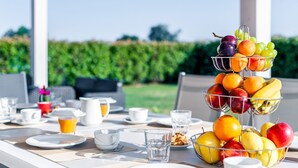 A breakfast table set outdoors with a fruit basket, plates, cups, and a pitcher of orange juice. - Stunning private villa for 13 people with A/C, private pool, WIFI, hot tub, sauna, TV and patio (Cintolese)