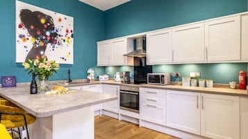 A modern kitchen with white cabinets, a central island, and a teal accent wall.