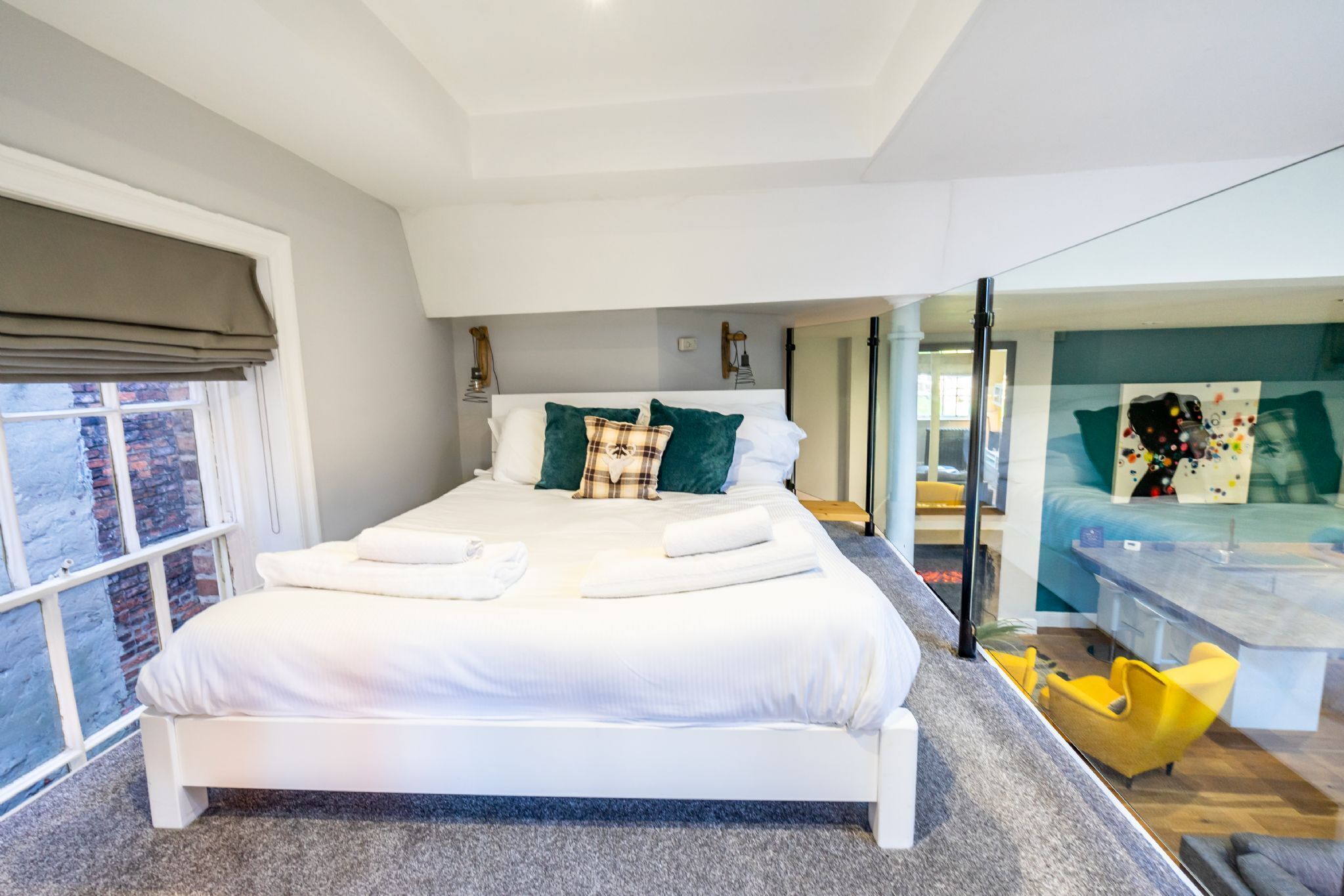 A modern hotel room with a large bed, a desk, and a view of the city.