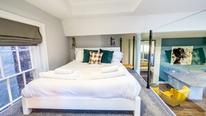 A modern hotel room with a large bed, a desk, and a view of the city. - The School House - sleeps 2 guests  in 1 bedroom (York)
