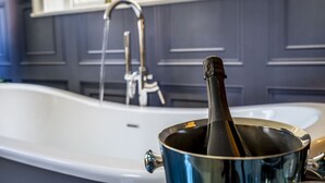 A bathtub with a faucet and a bottle of champagne in a bucket. - The School House - sleeps 2 guests  in 1 bedroom (York)