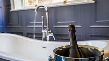A bathtub with a faucet and a bottle of champagne in a bucket.