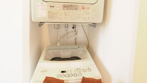Une machine à laver blanche, dotée d’un panneau de commande et d’une étiquette, se trouve dans une salle de bain.
