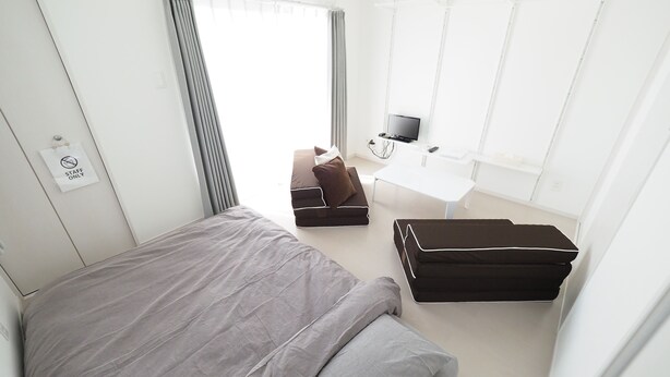 Une chambre d’hôtel moderne équipée d’un lit, d’un bureau, d’une télévision et d’une fenêtre avec des rideaux.