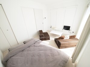 Un dormitorio con cama, sofá, escritorio y televisor.
