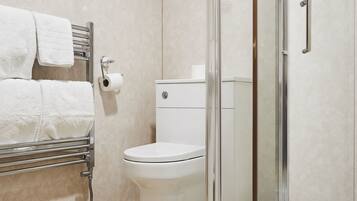 Une salle de bain avec une douche à parois de verre, des toilettes et un porte-serviettes avec des serviettes.