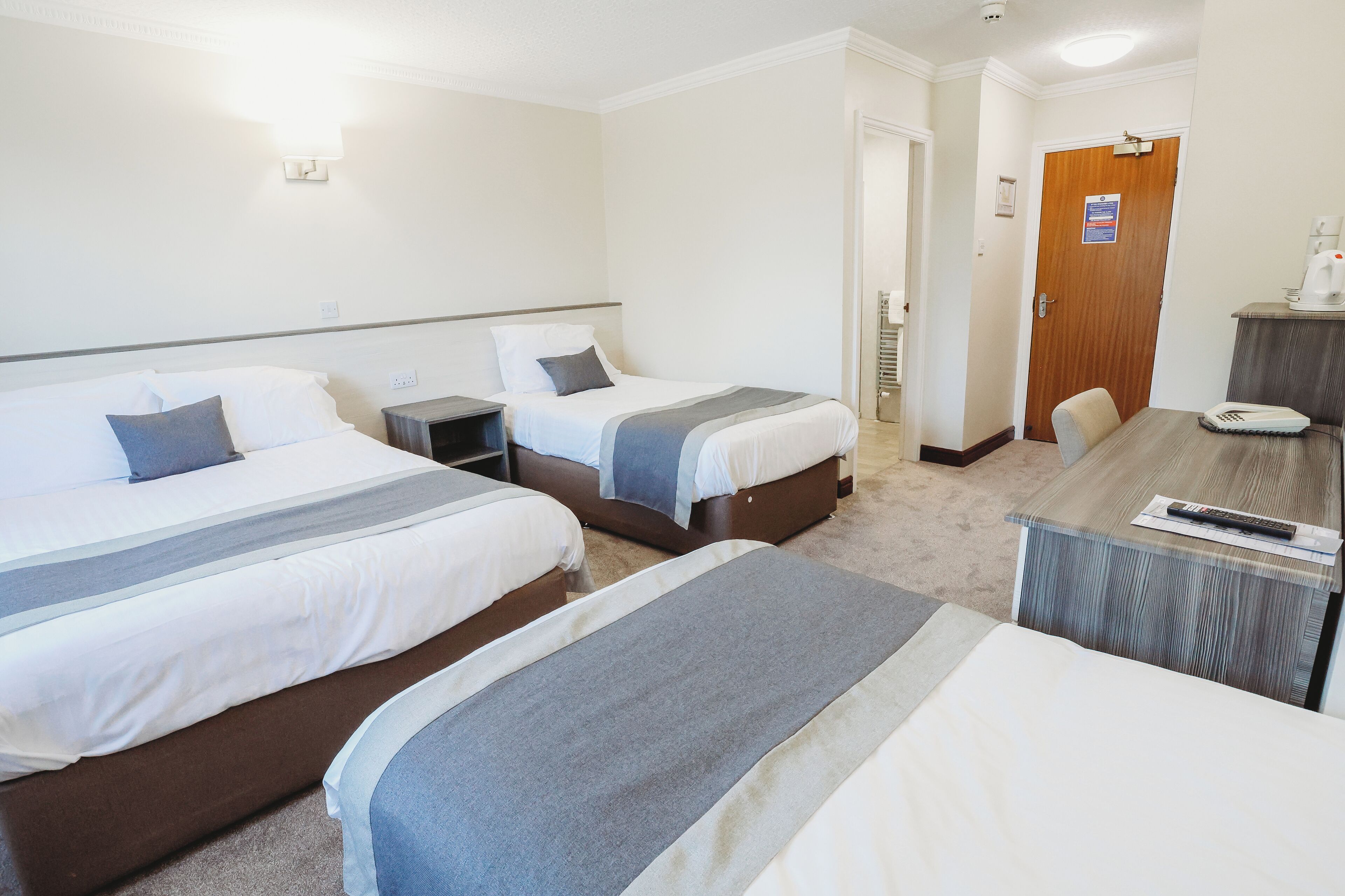 A hotel room with two beds, a desk, and a chair.