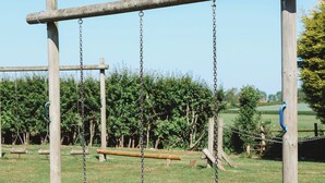 A wooden swing set with tire swings in a grassy area. - Appleby Inn Hotel (Swadlincote)
