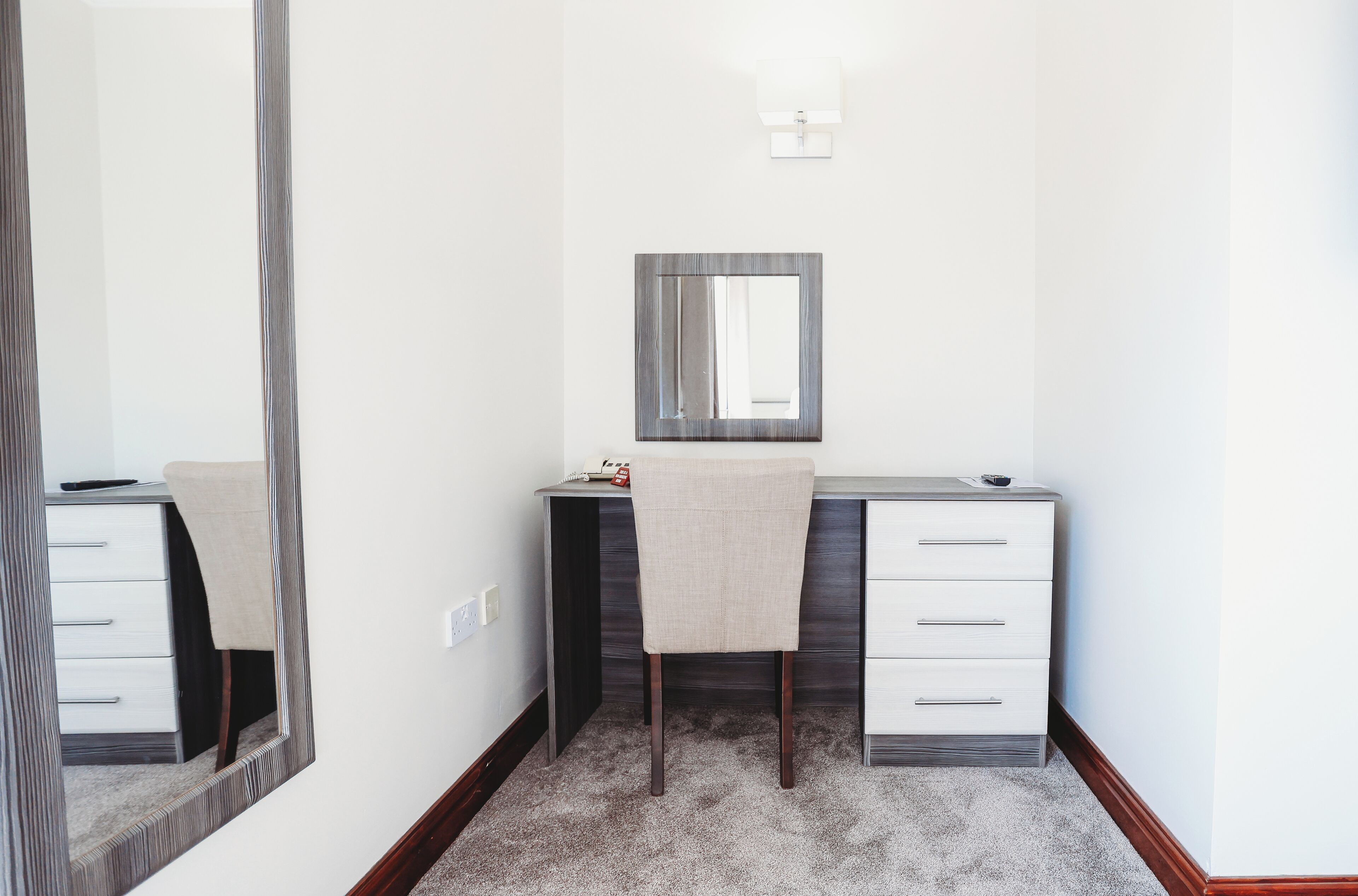 Un baño pequeño y moderno con tocador, espejo y luminaria.