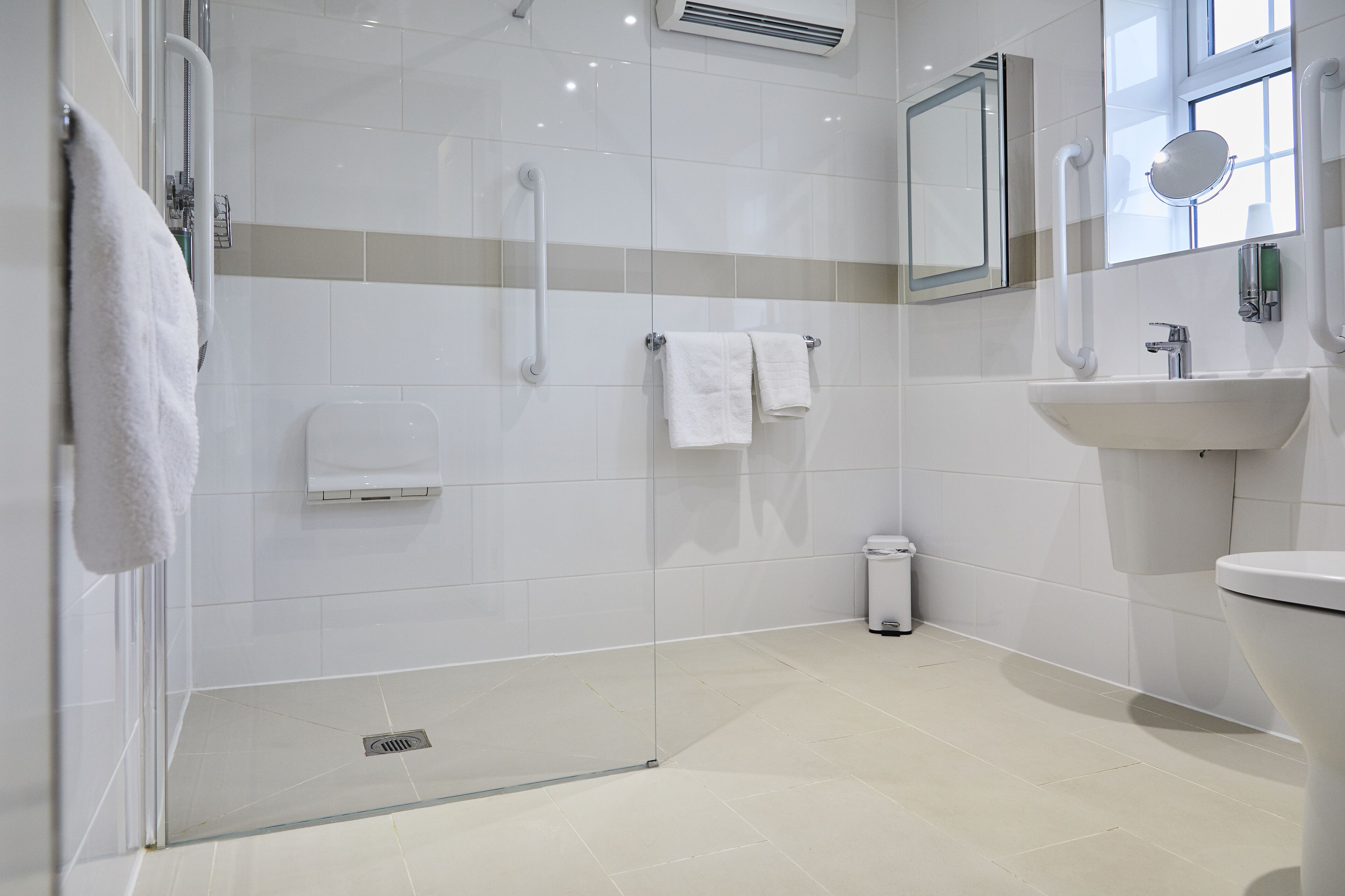 Un bagno moderno con box doccia in vetro, lavandino e specchio.