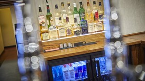 A bar area with various liquor bottles and a refrigerated display case with beverages. - Appleby Inn Hotel (Swadlincote)