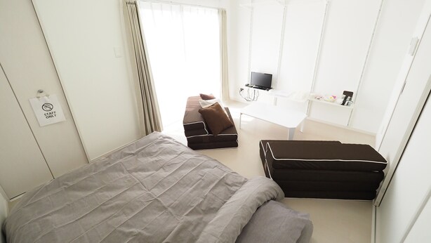 Ein Hotelzimmer mit Bett, Sofa, Fernseher und Schreibtisch.