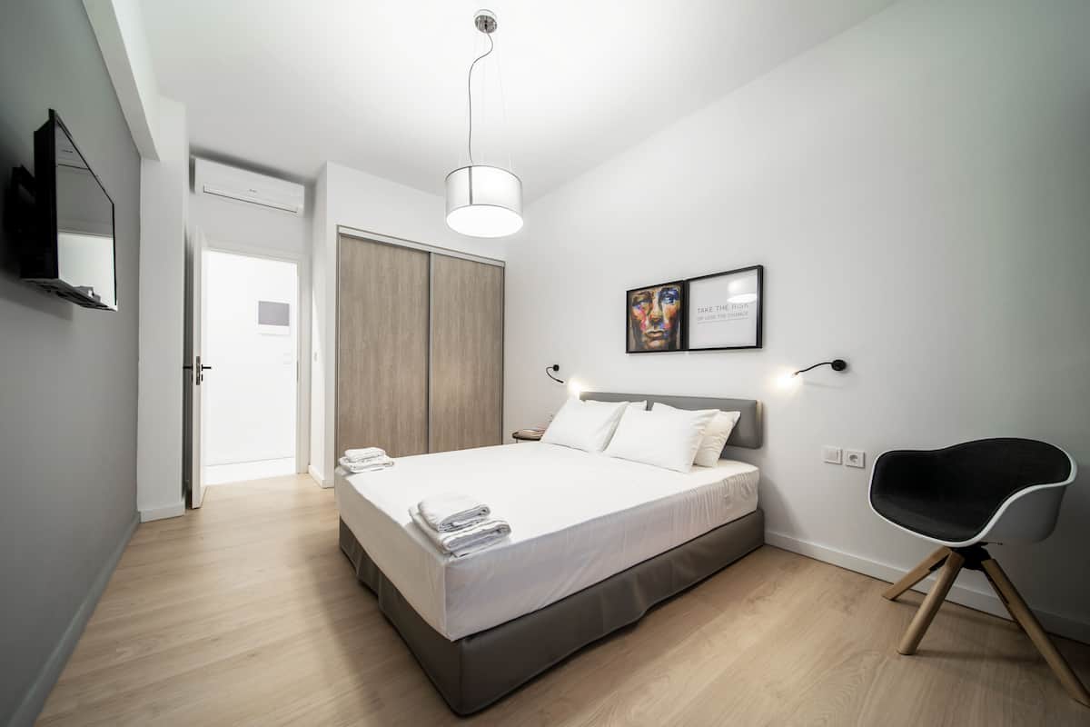 Quarto moderno com cama, mesa de cabeceira e uma cadeira.