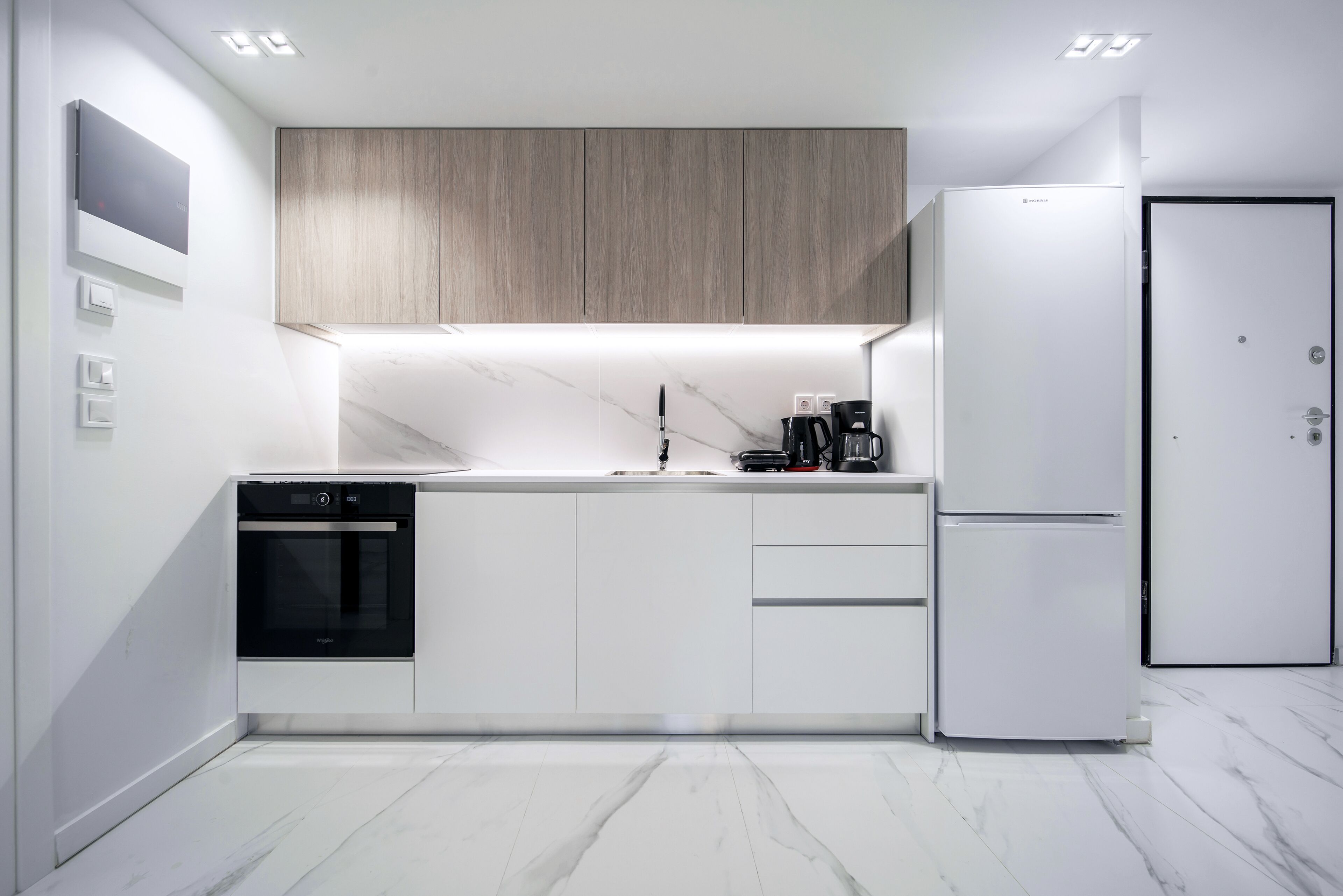 A modern kitchen with a built-in oven, a refrigerator, and a coffee maker.