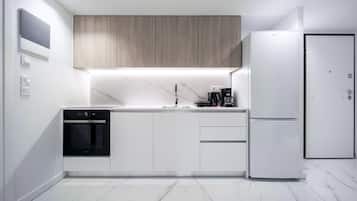 A modern kitchen with a built-in oven, a refrigerator, and a coffee maker.