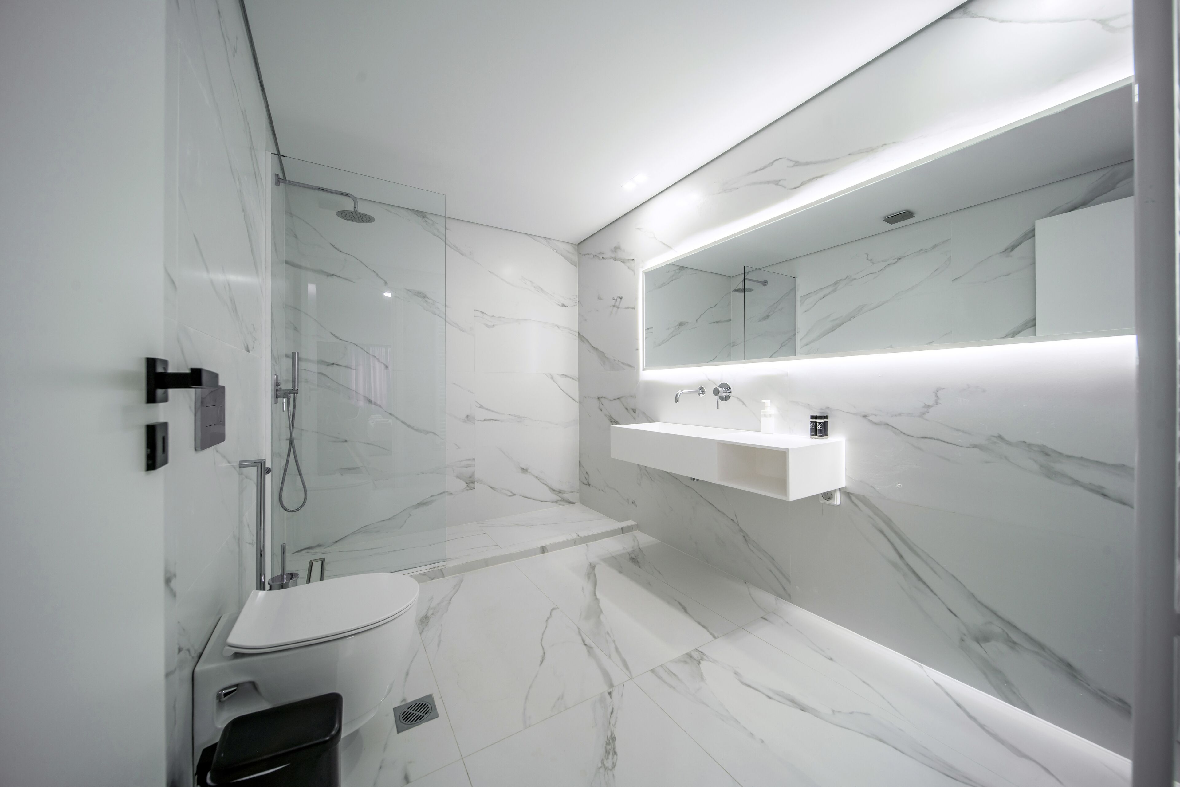 A modern bathroom with a white sink, mirror, and shower.