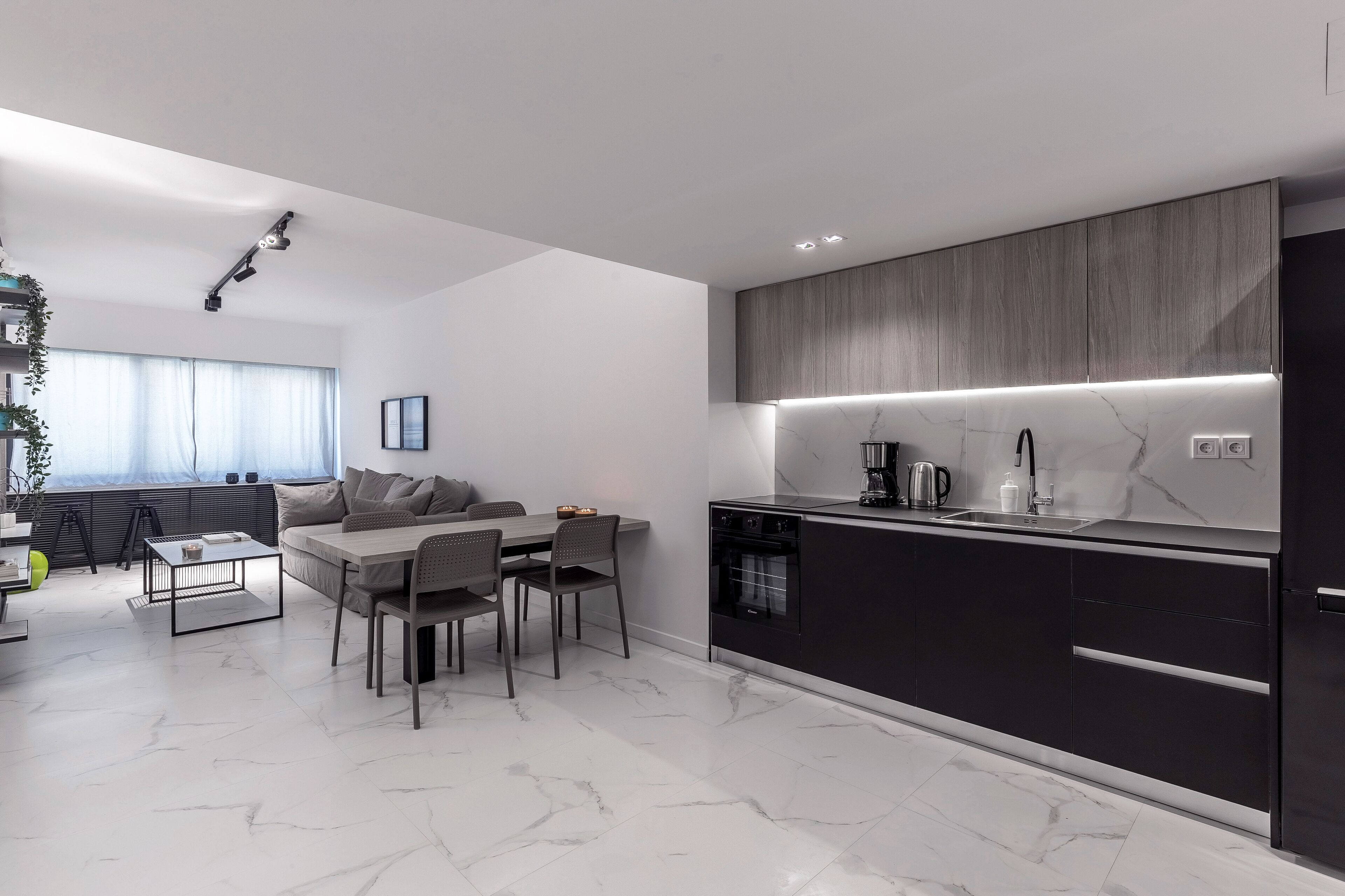 A modern kitchen with a marble countertop, dark cabinetry, and a built-in oven.
