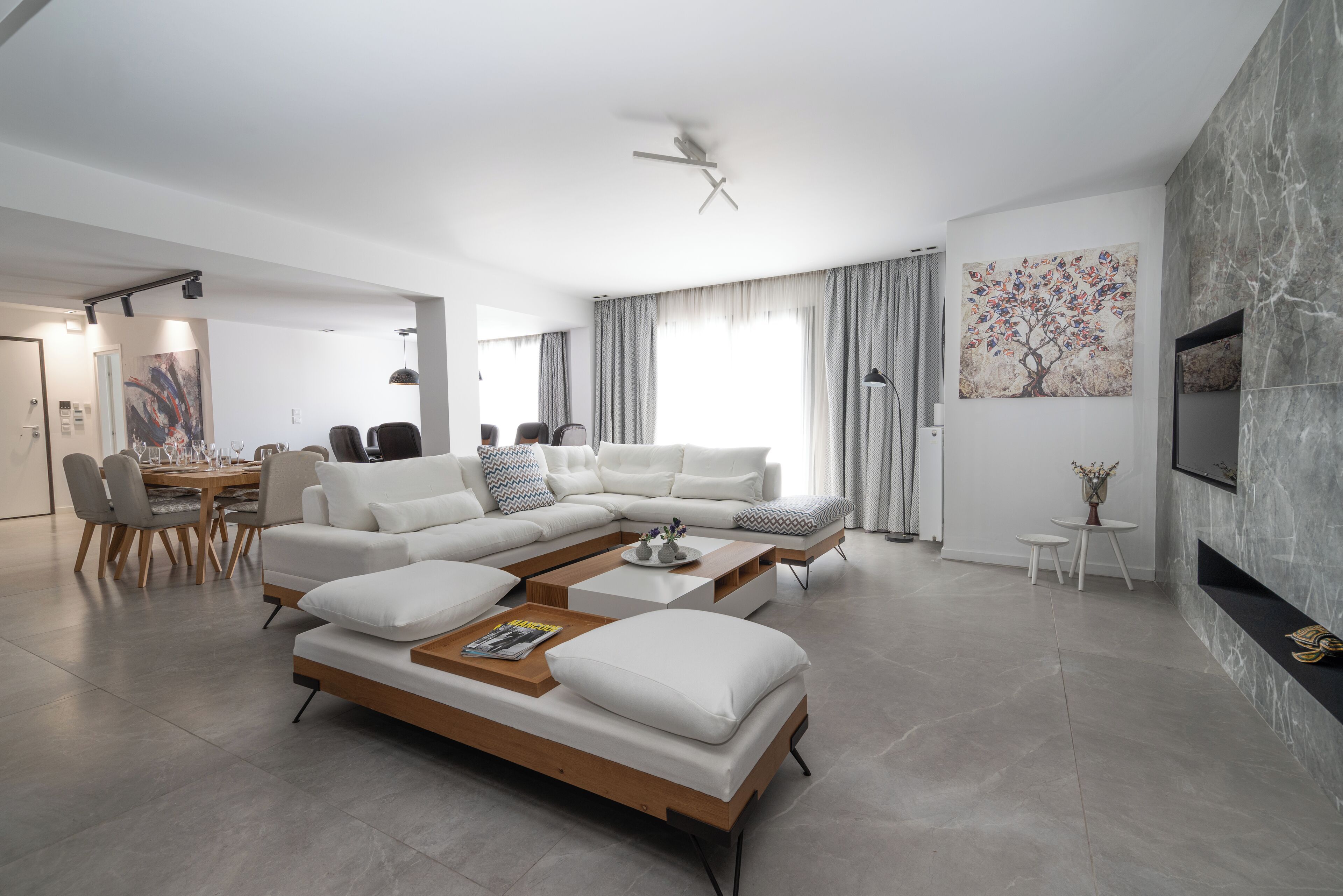 A modern living room with a sectional sofa, a coffee table, and a dining area with chairs and a table.
