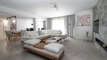 A modern living room with a sectional sofa, a coffee table, and a dining area with chairs and a table.