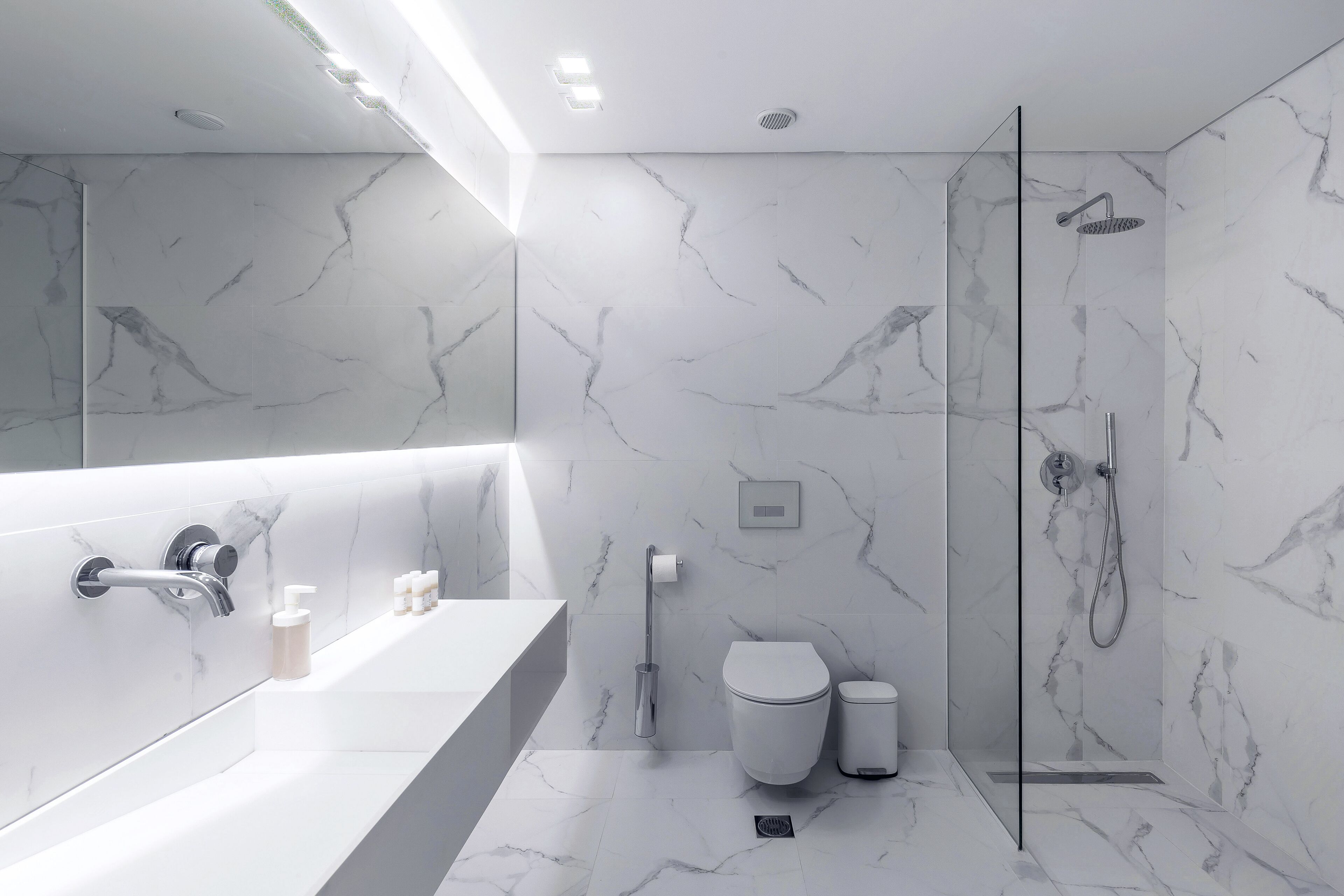 A modern bathroom with a glass shower enclosure, a white bathtub, and a toilet.