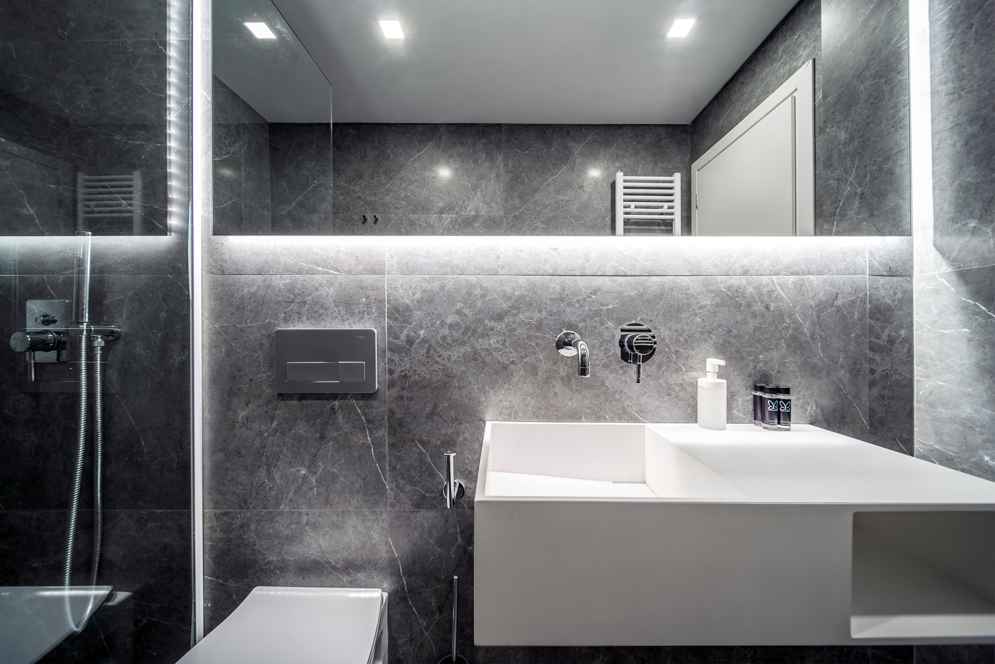 A modern bathroom with a large white sink, a mirror, and a shower area.