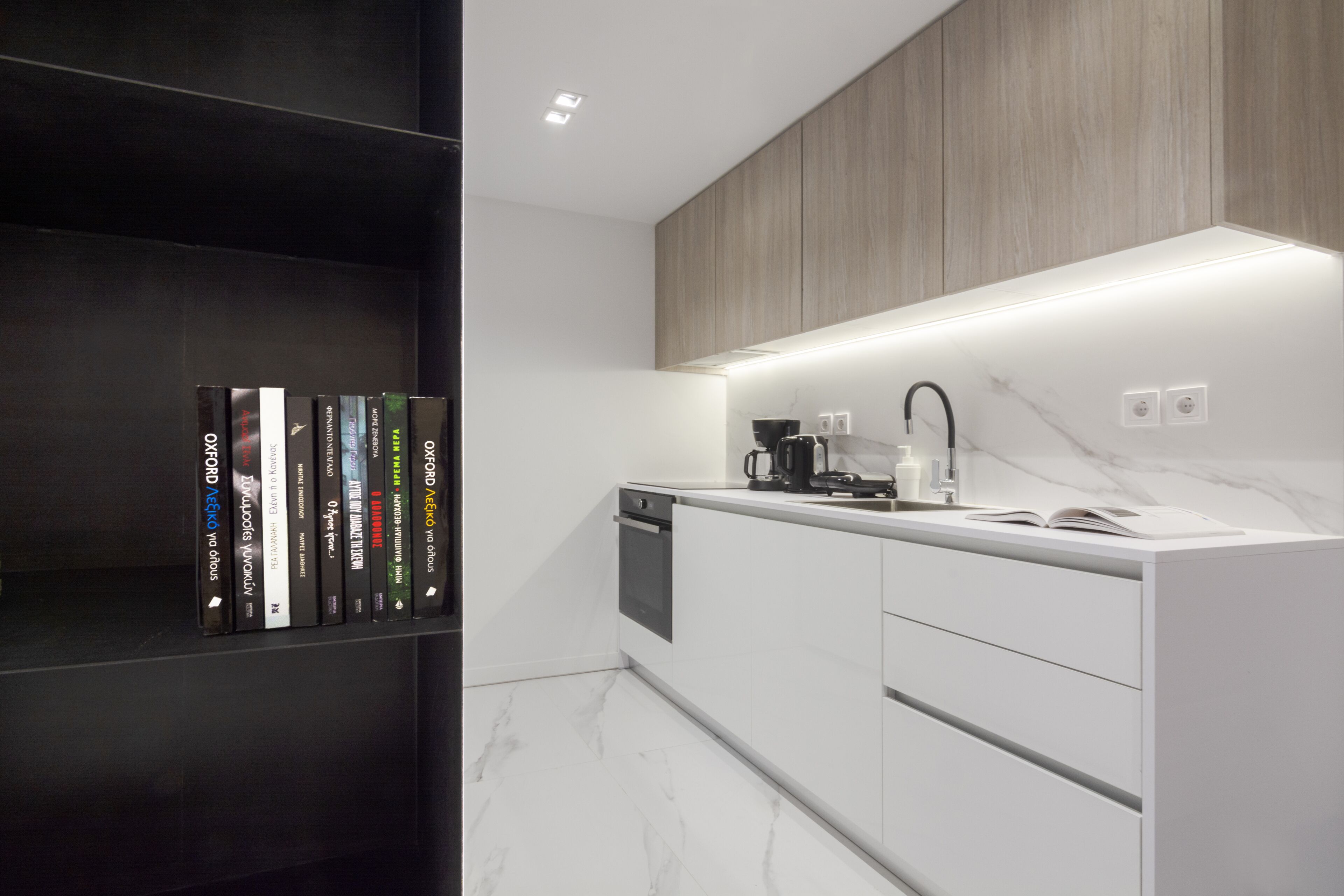 A modern kitchen with white cabinets, a marble countertop, and a built-in oven.