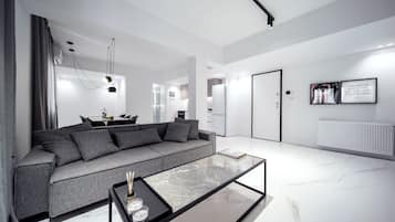 A modern living room with a grey sofa, a glass coffee table, and a minimalist design.