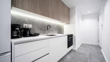A modern kitchen with white cabinets, a marble backsplash, and a built-in oven.
