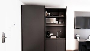 Una cocina moderna con un mueble oscuro, un microondas y una cafetera.