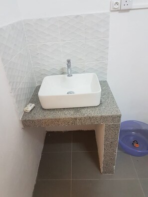 A bathroom with a white sink on a granite countertop, a tiled wall, and a blue basin.